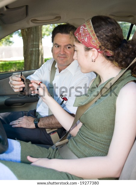 Driving\
instructor handing a teen girl the car\
keys.