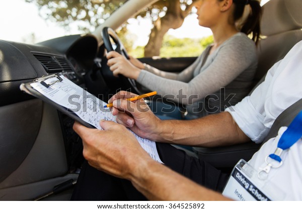driving instructor inside a car with student\
driver doing checklist