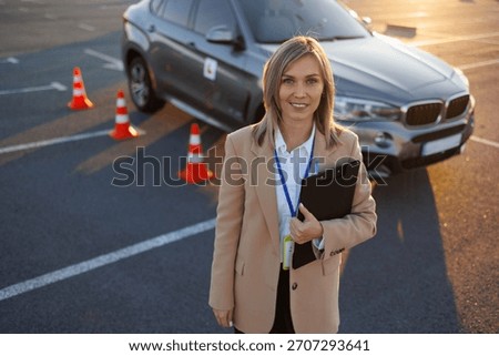 Driving instructor standing in front of learner vehicle during practice session