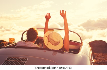Driving into the Sunset. Happy Young Couple Enjoying the Sunset in Classic Vintage Sports Car