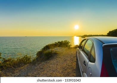 Driving into the sunset, Driving sport car and rear view mirror into the sunset with the countryside sea water horizon rolling by on a summer day. concept for business, speed or success