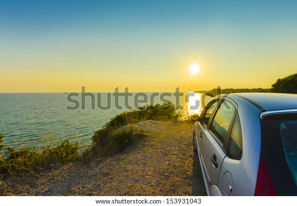 Driving into the sunset, Driving sport car and
rear view mirror into the sunset with the countryside sea water
horizon rolling by on a summer day. concept for business, speed or
success