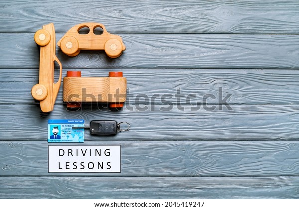 Driving\
license with key and cars on wooden\
background