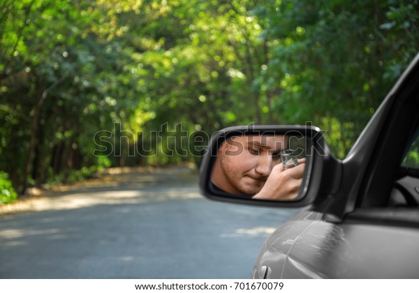 A\
driving man with an alcohol in a rearview mirror on a blurred\
background. Drinking and driving concept. Copy space.\

