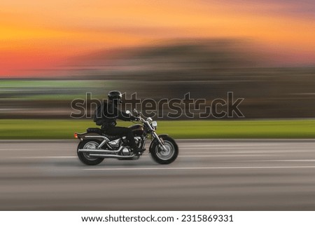 Driving motorcycle with speed blurred background. A speeding motorcycle on an asphalt street. Motion blur.