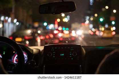Driving in New York at night. Interior view of taxi cab in traffic. Close up view on the dashboard. Colorful bokeh lights out of the window