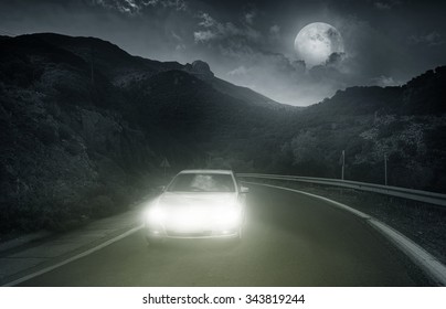 Driving On An Asphalt Road Towards The Headlights Of Car At Night 