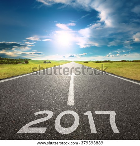 Driving on an empty road towards the sun to upcoming 2017 through idyllic scenery. Concept for success and passing time.
