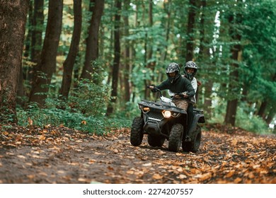 Manejando por el sendero. Una pareja joven montando una quad en el bosque.