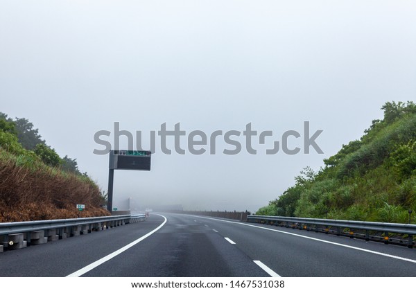 Driving on\
the high way at moody foggy landscape\
view.