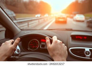 driving on highway road, closeup hands of car driver on steering wheel, road trip at sunset - Powered by Shutterstock