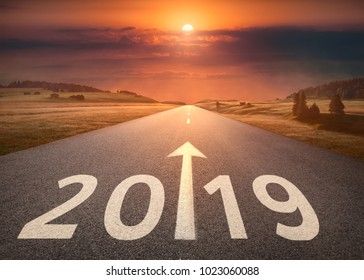 Driving on idyllic open road against the setting sun forward to new year 2019. Concept for success and future.