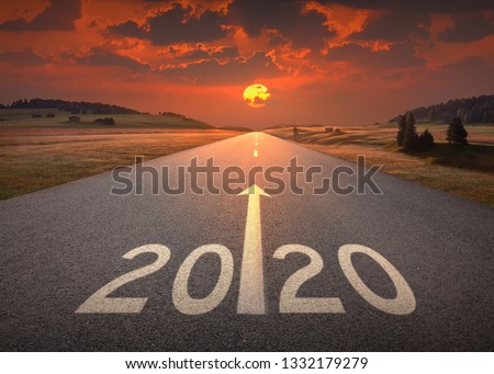 Driving on idyllic open road against the setting sun forward to upcoming 2020 new year. Concept for success and future.