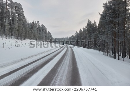 Driving on snowy winter roads of Finnish Lapland, arctic landsape, icy asphalt
