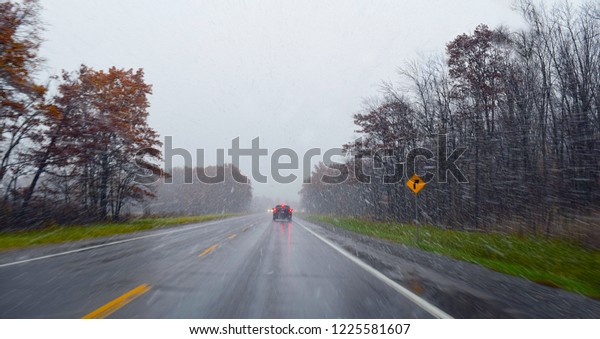 Driving in poor wintry\
weather conditions on a wet, snowy road with rain and sleet on a\
highway. Image ideal for safety posters, travelling warnings, with\
room for text.