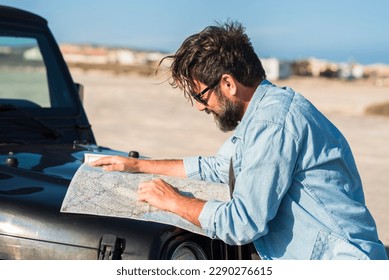 Driving problems. One man driver lost on the roads use paper old guide map to find destination. People and transport lifestyle adventure tourism. Summer country side desert in background. Journey - Powered by Shutterstock