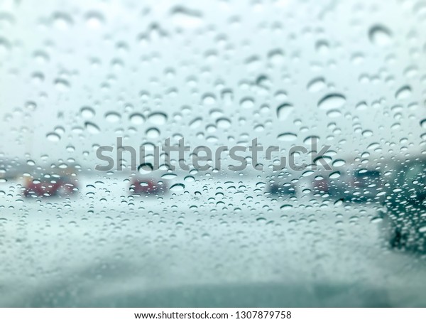 Driving in rain, Blurred Car windshield with rain\
drops. - Image
