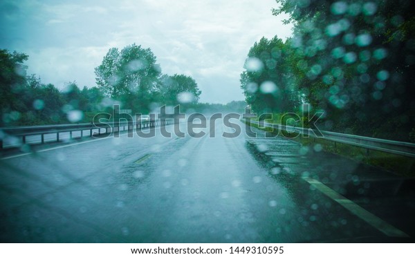 Driving in rain. Car and the road in the rain\
through the front\
window