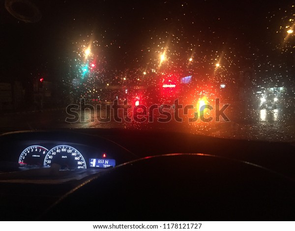 Driving in the rain, falling in the night, light\
of car and traffic\
lights.
