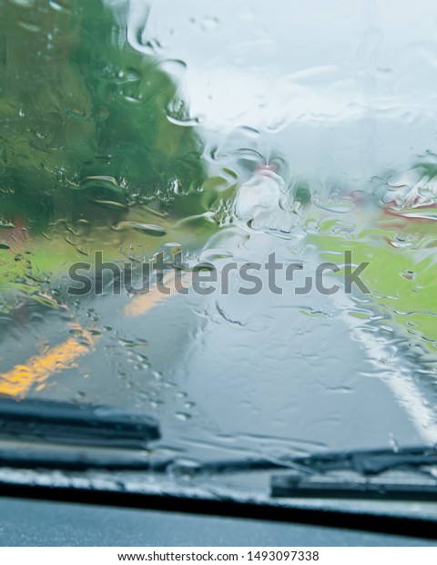 Driving in rain. Motion blurred image.\
Focused on rain on the windscreen whilde\
driving.