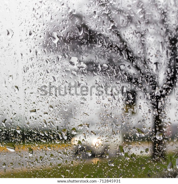 Driving in rain.\
Raining and wet weather driving conditions on the road, traffic\
blurred, raindrops on\
car.