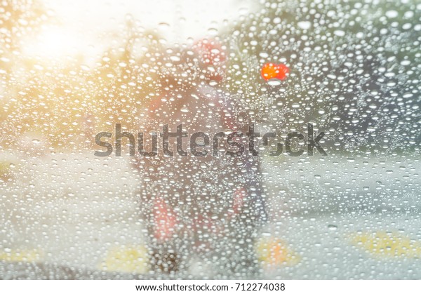 Driving in rain at sunset. Road view through car\
window with rain drops.