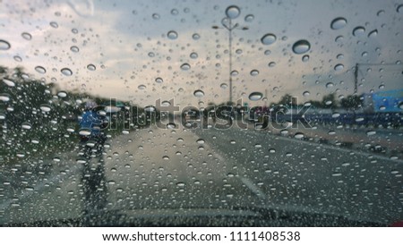 Driving in the rain view from inside car with rain drops on car windshield. Road view through car window.Selective focus. 