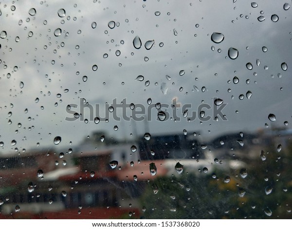 Driving in the rain.Driving in the rain, view\
through the car glass. Rain drops on outside car mirror window\
glasses surface with cloudy background . Natural pattern of\
raindrops on cloudy\
background.