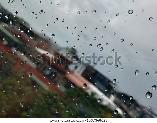 Driving in the rain.Driving in the rain, view
through the car glass. Rain drops on outside car mirror window
glasses surface with cloudy background . Natural pattern of
raindrops on cloudy
background.