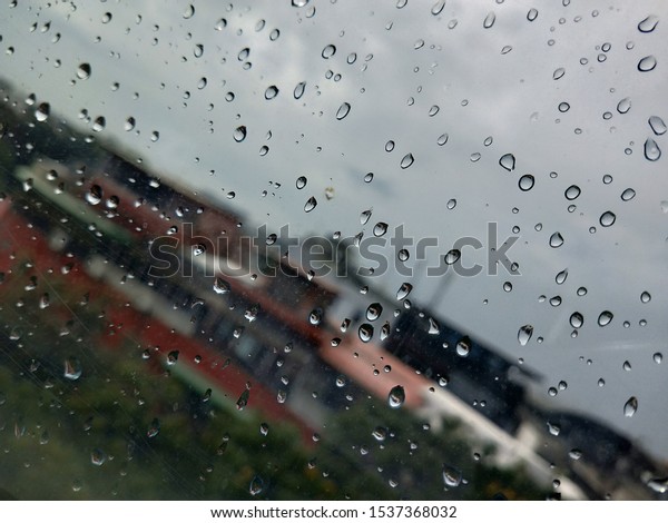Driving in the rain.Driving in the rain, view\
through the car glass. Rain drops on outside car mirror window\
glasses surface with cloudy background . Natural pattern of\
raindrops on cloudy\
background.