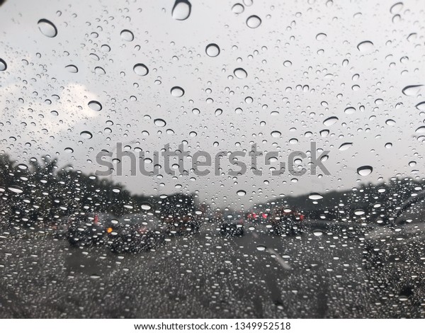 Driving in the rain.View from the car with\
rain drop on the car\
windshield.