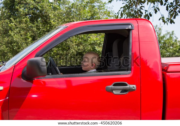 driving a red pickup truck\
sitting boy