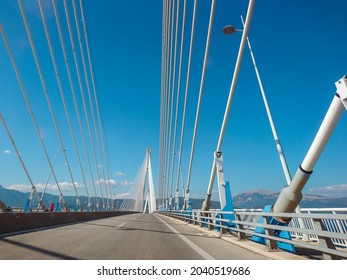 Driving Rion-Antirion Bridge on highway road in Patras city, Greece. Suspension bridge on Corinth Gulf. Second longest cable-stayed bridge. Sunny summer day with scenic blue sky