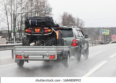 Driving safety on a wet slippery road with a single-axle trailer — SUV car fast carries a Quad bike after rain, aquaplaning dangerous