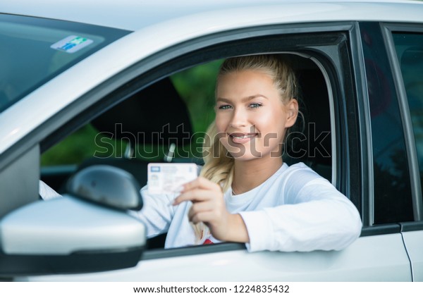 Driving school.
Attractive young woman proudly showing her drivers license. Free
space for text. Copy space.

