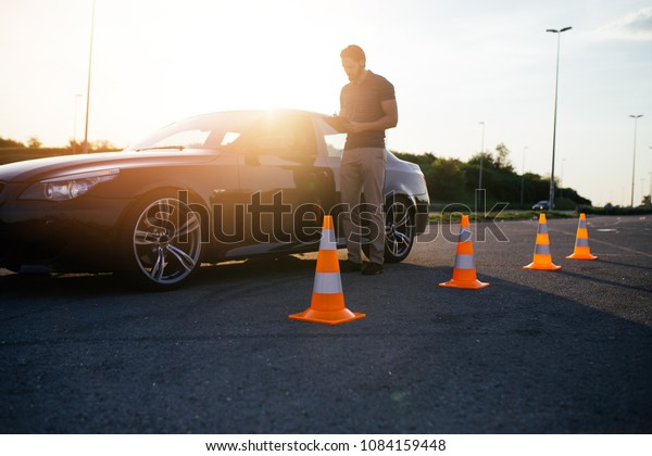 Driving school or\
test. Beautiful young woman with instructor learning how to drive\
and park car between\
cones.