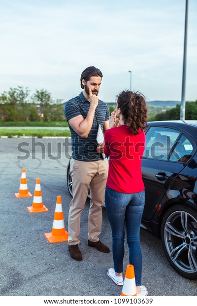 Driving school or\
test. Beautiful young woman with instructor learning how to drive\
and park car between\
cones.