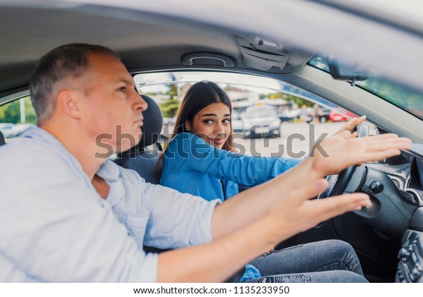 Driving school or test.\
Beautiful young woman learning how to drive car together with her\
instructor. Learning to Drive. Woman getting a driving lesson in\
the car