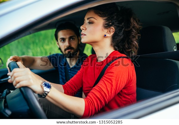 Driving school or test.\
Beautiful young woman learning how to drive car together with her\
instructor. 