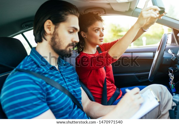 Driving school or test.\
Beautiful young woman learning how to drive car together with her\
instructor.