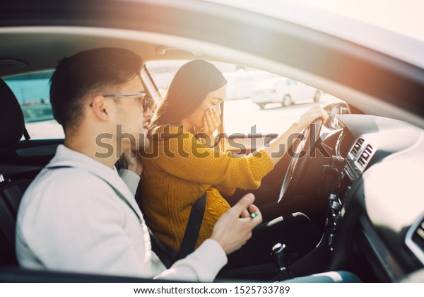 Driving school\
or test. Beautiful young pregnant woman learning how to drive car\
together with her instructor.\
