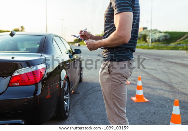 Driving school or test. Driving instructor\
writing notes after parking\
lesson.