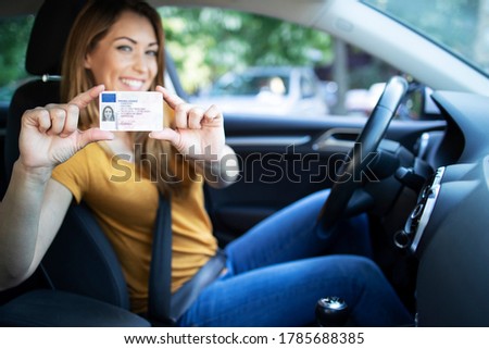 Driving school. Young beautiful woman successfully passed driving school test. Female smiling and holding driver's license. Girl with driving license.