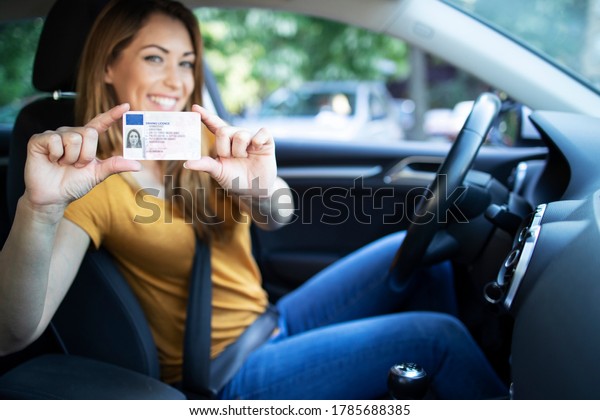 Driving school. Young beautiful woman\
successfully passed driving school test. Female smiling and holding\
driver\'s license. Girl with driving\
license.