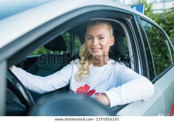 Driving\
school. Young happy woman - student sitting in a car and looking at\
the camera. Free space for text. Copy\
space.\
