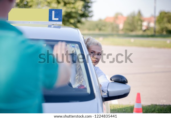 Driving school. Young woman or driving student  with\
instructor learning how to drive and park car between cones. Copy\
space. 