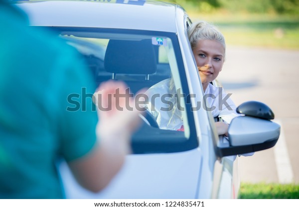 Driving school. Young woman or driving student with
instructor learning how to drive and park car between cones. Copy
space. Lens flare
