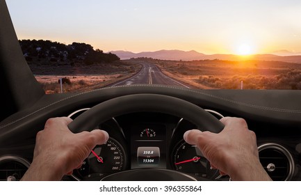 Driving at sunset. View from the driver angle while hands on the wheel.