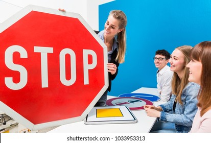 Driving Teacher Explaining Meaning Of Street Signs To Class Of Students