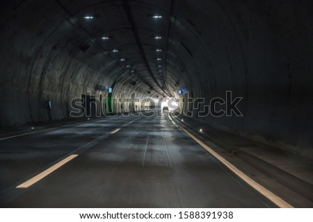 Driving through a dark tunnel on a freeway with a view of the light at the end of the tunnel